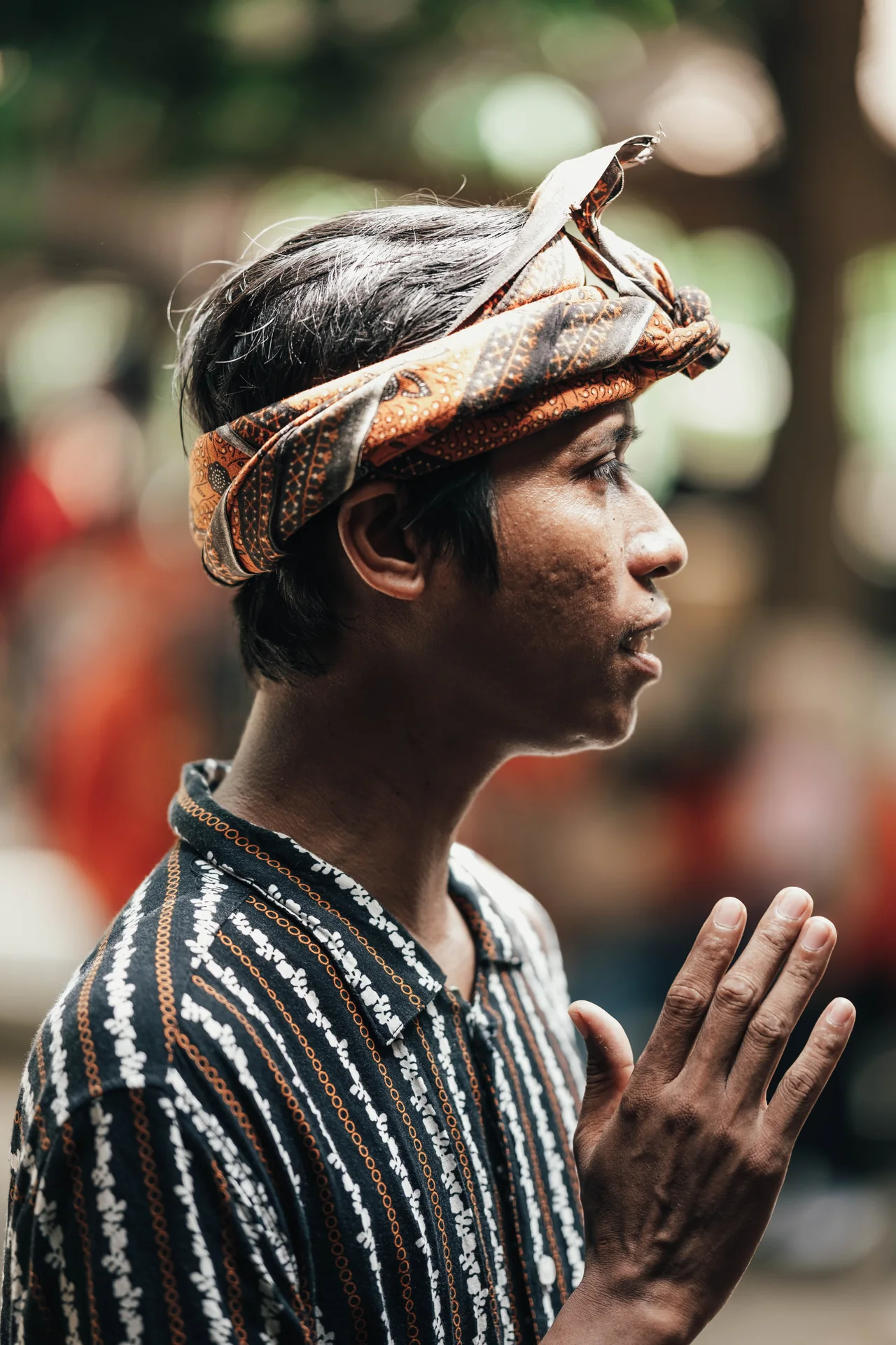 Man in a patterned headcloth with hands together in profile