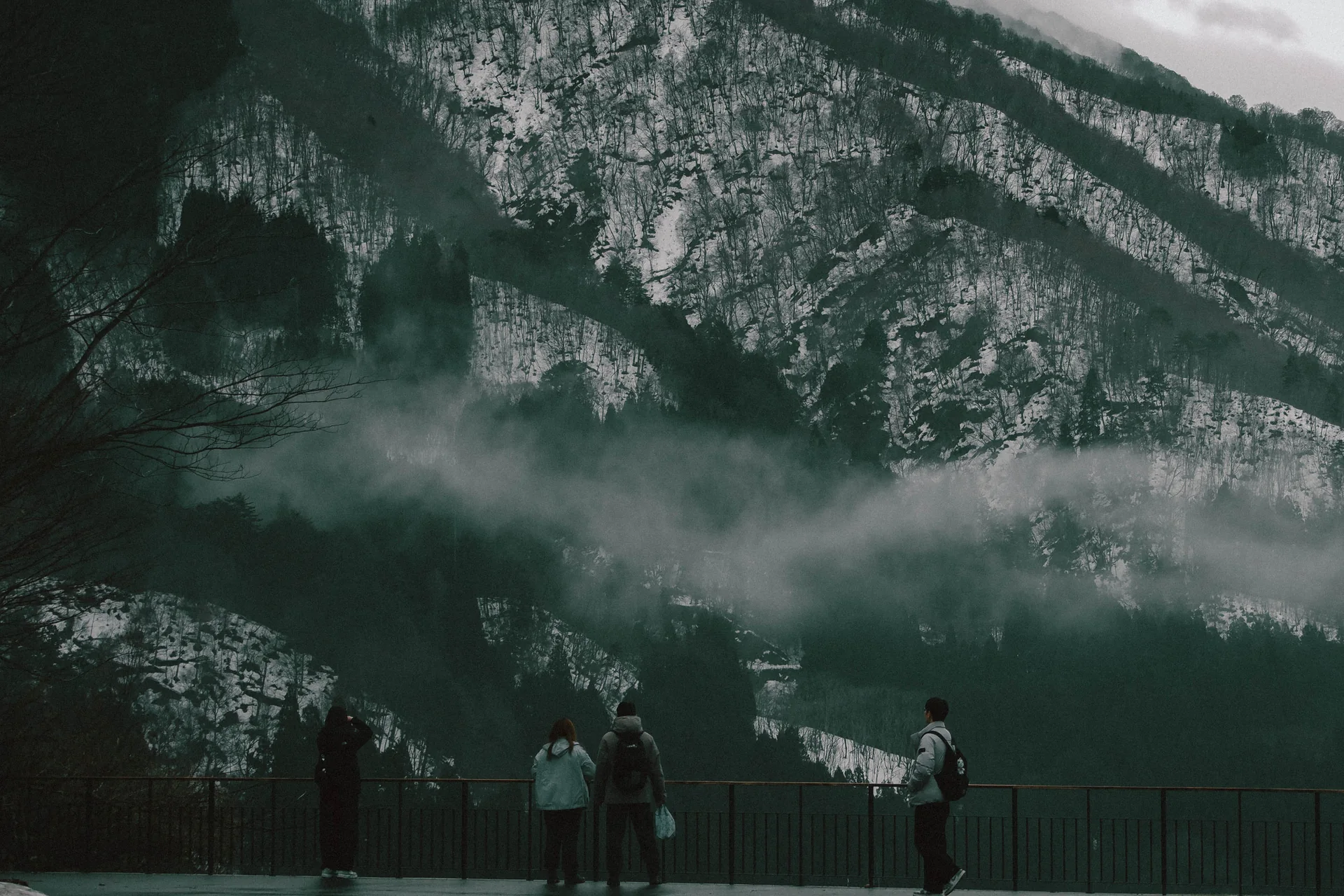 People below snowy misty mountains